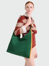 Bolso tipo hobo de gran tamaño en color verde, con detalles laterales en naranja y correa de hombro integrada. Presenta un diseño minimalista con cierre de botón a presión.
