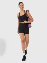 Top deportivo tipo crop top color negro con sujetador interior integrado, escote redondo y diseño de tiras delgadas cruzadas en la espalda.