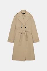 Trench largo beige con cuello de solapa, cierre frontal cruzado con doble botonadura y cinturón ajustable del mismo tejido. Cuenta con bolsillos delanteros de vivo, mangas largas con trabillas en los puños y detalles de solapas en los hombros.
