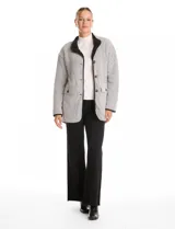 Cardigan de tejido de punto con diseño de espiga en color beige, totalmente forrado en corderito sintético blanco. Presenta cuello solapa, cierre frontal con botones, bolsillos tipo parche con solapa y terminaciones con vivos en contraste.