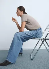 Pantalón jeans de tiro alto y corte wide leg, confeccionado en tejido de algodón con elasticidad. Presenta diseño de cinco bolsillos, cierre frontal con botón y cremallera, y trabillas para cinturón.