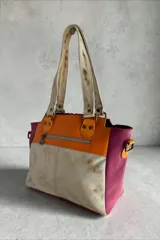 Cartera de cuero de diseño exclusivo con intervención artística de Carolina De Cunto, combinando tonos naranja, azul y detalles en color natu y terra. Cuenta con doble asa de hombro, solapa frontal de pelo sintético azul y herrajes metálicos.