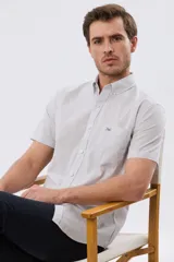 Camisa de manga corta con patrón de cuadros pequeños, cuello abotonado y bolsillo frontal en el pecho. Cuenta con cierre de botones y calce slim.