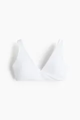 Top deportivo blanco para yoga, con escote en V, breteles anchos y detalle girado en el frente. Incluye copas forradas con relleno extraíble.