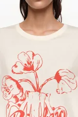 Remera oversize color blanco crudo, confeccionada en algodón, con cuello redondo y mangas cortas. Presenta un estampado frontal en color rojo de un jarrón con flores y el logo de la marca en caligrafía.