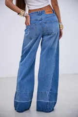 Jean de corte wide leg con tiro medio, confeccionado en denim rígido sin elastano. Presenta un diseño de paneles con costuras verticales y un ruedo con detalle de costura horizontal y terminación desflecada.