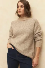 Polera beige de tejido de punto con cuello alto y mangas largas.