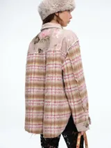 Camisa de corte oversize confeccionada en tejido de textura suave con estampado de cuadros y detalles de patchwork floral en los bolsillos delanteros, cuello y tapeta de botones. Presenta bordes deshilachados, cierre frontal con botones metálicos y dos bolsillos con solapa en el pecho.