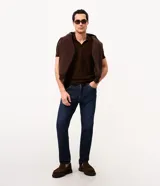 Remera polo de hombre en color marrón, confeccionada en tejido texturizado con mezcla de algodón y poliéster, de manga corta y cuello abierto sin botones.