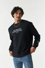 Buzo negro de felpa con cuello redondo y lettering estampado en el frente con la frase 'Always Grateful' y la marca 'Mistral'.