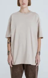 Remera de corte crop y calce oversize, con hombros caídos, confeccionada en algodón premium americano color beige claro. Posee cuello redondo rib al tono y doble costura.