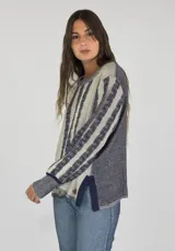 Sweater de punto con diseño de rayas verticales en tonos beige y azul marino, con textura trenzada, cuello redondo, mangas largas y aberturas laterales en el ruedo.
