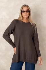 Buzo de punto color marrón chocolate, con cuello redondo, corte relajado y mangas largas con puños acanalados. Presenta detalles de costuras verticales decorativas en el ruedo.