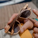 Lentes de sol con marco redondo de madera en tonos claros y oscuros, con cristales degradados en color marrón.