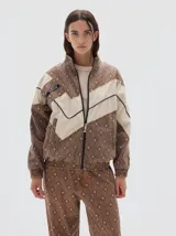 Campera de estilo deportivo con cierre frontal, confeccionada en denim con estampado de rombos en tonos marrones y paneles en color crudo. Presenta cuello alto, puños y cintura elásticos, y detalle de etiqueta con logo en el pecho.