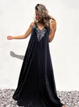 Vestido largo de corte holgado en color negro, con escote en V profundo decorado con lentejuelas negras brillantes. Presenta un diseño sin mangas y una caída fluida.