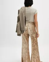 Pantalón de terciopelo color dorado, de tiro alto, silueta amplia y acampanada, con cintura elástica y pliegues en toda la prenda.