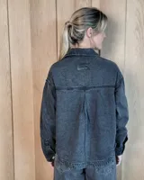 Sobrecamisa de denim con diseño de rayas verticales, corte holgado, cuello camisero, cierre frontal con botones y bolsillos delanteros aplicados.