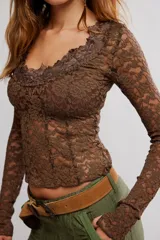 Remera de encaje floral blanca de manga larga y calce ajustado, con escote en V y diseño semitransparente.