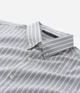 Camisa de corte regular confeccionada en una mezcla de bambú y poliéster, con diseño de rayas verticales en tono verde claro y blanco. Presenta cuello inglés, cierre frontal con botones y mangas largas con puños ajustables.