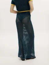 Conjunto de tejido calado color azul petróleo con detalles en amarillo. Incluye un cárdigan corto con botones y una falda larga recta con pretina elástica.