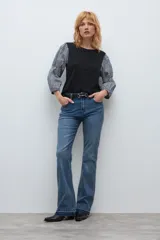 Jean de corte bootcut en color azul medio, con diseño de tiro medio y ruedo deshilachado.
