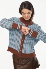 Cardigan de punto con patrón trenzado, color crudo y visón, con cuello solapa, cierre frontal de botones y mangas largas con puños elásticos rayados.
