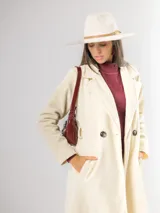 Tapado de paño sofisticado con solapas clásicas, cierre frontal de botones y bolsillos laterales. Presenta un diseño de corte recto y estructura elegante.