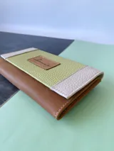 Billetera de cuero color camel con solapa verde lima y detalles en color crema. Tiene cierre con broche y monedero externo.