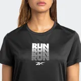 Remera deportiva Reebok de manga corta, color negro, con cuello redondo y un estampado frontal que repite la palabra "RUN" en blanco y gris, incluyendo el logo de Reebok.