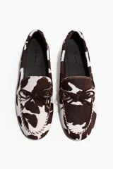 Zapatos náuticos de cuero con estampado animal print tipo vaca, con cordones delanteros y costuras decorativas.