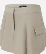 Short pollera beige de sarga con bolsillos cargo laterales y solapa, cintura ancha, pliegues delanteros y cierre frontal discreto.