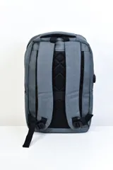Mochila gris con detalles en negro, con dos compartimentos principales con cierre, un bolsillo frontal con cierre y bolsillos laterales.