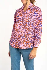 Camisa de viscosa color naranja con estampado animal print en tonos rosa y azul. Corte oversize, cuello clásico y cierre frontal con botones.