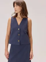 Chaleco negro sin mangas, de corte recto y largo a la cintura, con cuello redondo y cierre frontal oculto.