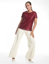 Blusa de manga corta con cuello redondo, confeccionada en tejido cubierto de lentejuelas color verde esmeralda. Cuenta con forro interno a tono y un corte recto.