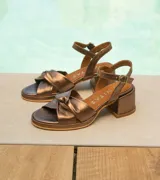 Sandalias de cuero color dorado, con plataforma y taco cuadrado. Presentan tiras cruzadas en el empeine y pulsera al tobillo con hebilla.