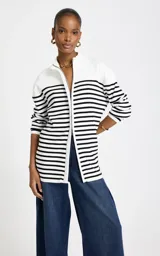 Cardigan de punto Le lis Blanc, color blanco con rayas horizontales negras, cuello alto con cierre frontal y mangas largas.