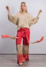 Pantalón de viscosa con estampado degradado de color rojo en la parte superior y beige en la parte inferior. Tiene un lazo en la cintura.