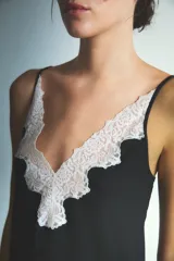 Conjunto de pijama compuesto por una musculosa con escote en V profundo decorado con encaje blanco y un short a juego. El diseño es de color negro, con breteles finos y corte holgado.