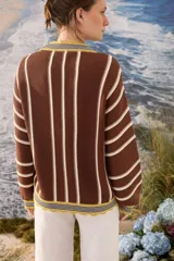 Cardigan de punto a rayas verticales en tonos marrón chocolate, blanco y amarillo, con escote en V, mangas largas y cierre frontal con botones.