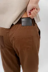 Pantalón de gabardina azul marino, de corte barrel y tiro bajo, con detalles en pana marrón en la pretina y en el ruedo interior vuelto.