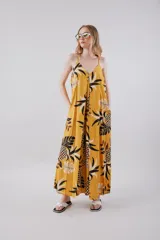 Vestido largo amarillo con estampado de hojas de palmera en blanco y negro, con breteles finos y botones en el frente.