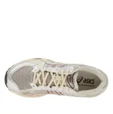 Championes Asics Gel-Kayano 14, en color beige y plateado con detalles en bordó, confeccionados con malla transpirable y superposiciones sintéticas, con suela amortiguada para mayor confort.