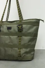 Bolso tipo tote color verde militar con múltiples correas horizontales y verticales. Tiene doble asa de soga trenzada y cierre superior con cremallera.