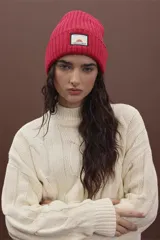 Gorro de punto fucsia con etiqueta de marca en el frente.