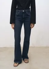 Jeans de tiro alto y corte flare, confeccionados en tejido de algodón estilo tejano vaquero. Presentan diseño de cinco bolsillos, trabillas para cinturón y cierre frontal con cremallera y botón.