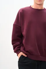 Buzo de cuello redondo color bordó, de corte amplio y mangas largas.