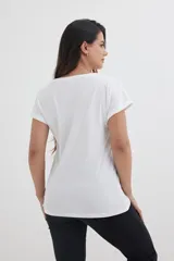 Remera blanca de algodón con mangas cortas y dobladillo. Estampado frontal de una estrella con lentejuelas de colores.