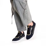 Championes Caterpillar Pause Retro T-Toe para mujer, color negro con detalles dorados y suela blanca. Confeccionados en cuero gamuzado con forro reciclado y plantilla de espuma EVA.